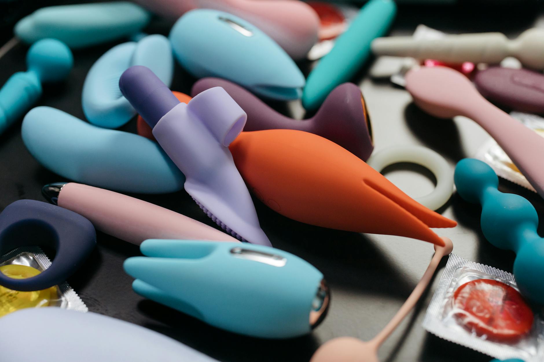 Manos sosteniendo un vibrador de succión azul elegante contra un fondo púrpura suave