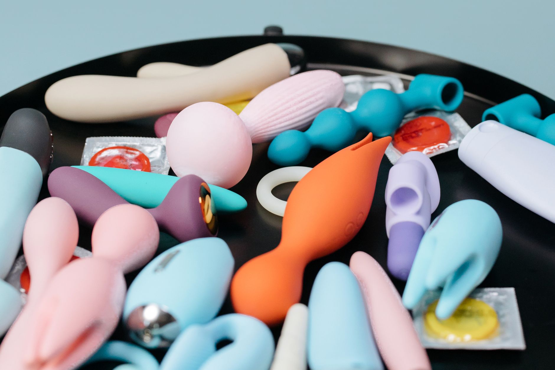 Colección vibrante de diversos juguetes sexuales en una bandeja negra, mostrando formas y colores variados