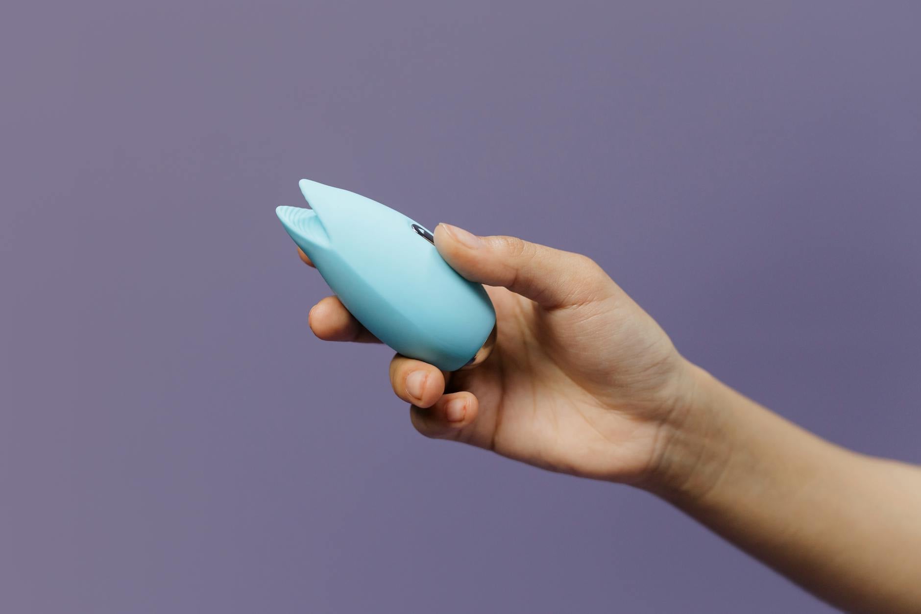 A silicone lemon vibrator held in hand against a purple background, representing pleasure restoration