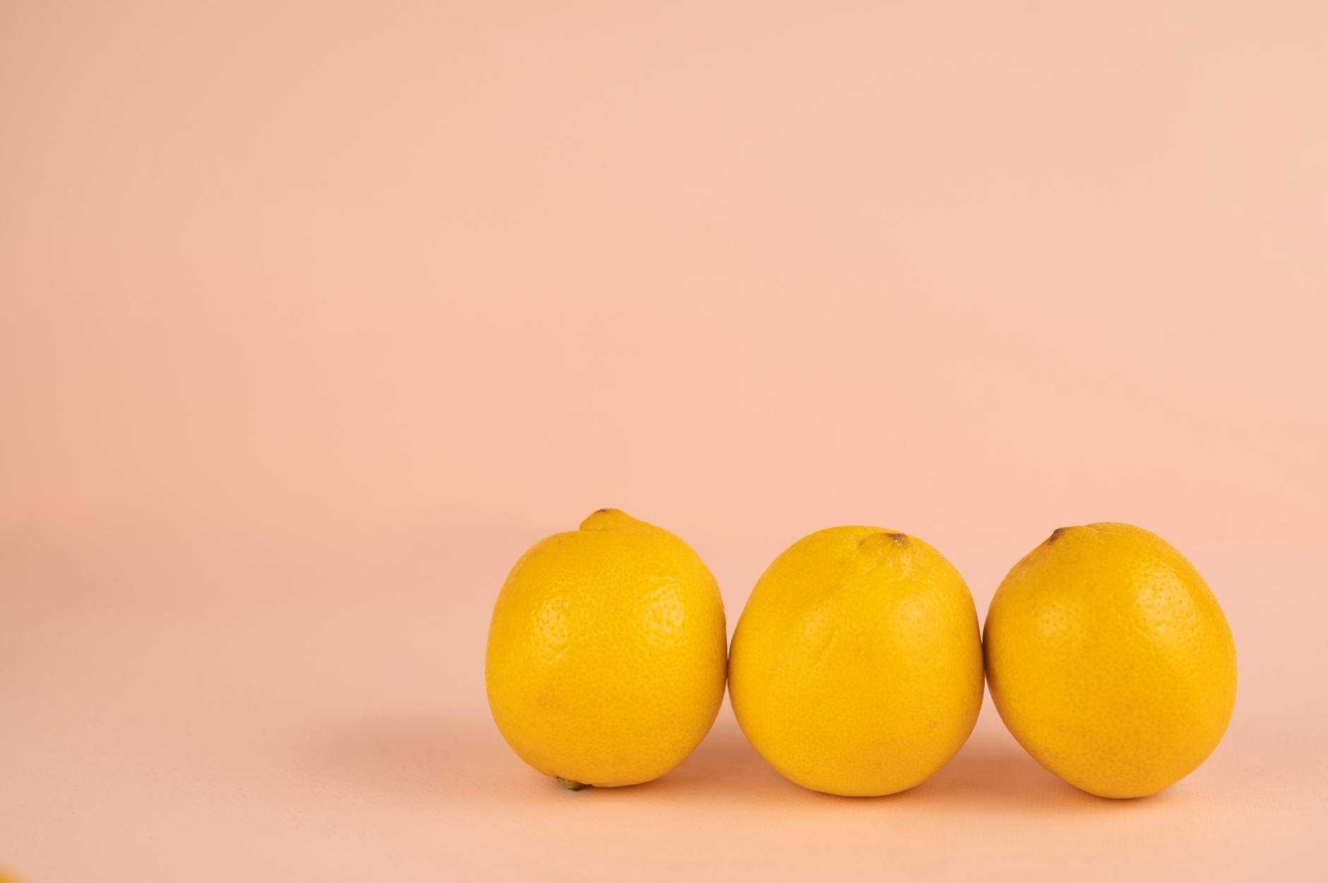 Limones frescos y vibrantes dispuestos sobre un fondo pastel suave, simbolizando el diseño natural del vibrador de limón